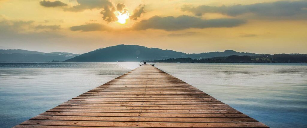 Person sitting at the end of a long dock at sunrise. ItalianLaw.net experts will help you to navigate through wills and other legal matters even if you live outside of Italy.