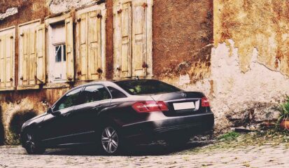 Old building and luxury sedan representing the Italian legal concept of scorpions - individuals who acquire what appears to be abandoned property adverse possession.